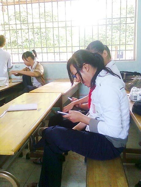 Học sinh vô tư sử dụng ĐTDĐ trong giờ học (Ảnh có tính minh họa ).