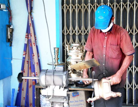 Ông Đinh Ngọc Thạch đang đánh bóng lư đồng bằng sáp.
