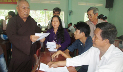 Thượng tọa Thích Huệ Minh và bà Lê Kim Huệ (giữa) trao quà cho các nạn nhân. 