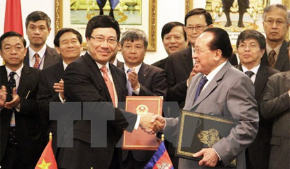 Phó Thủ tướng Phạm Bình Minh (trái) trao đổi Biên bản Thỏa thuận của Kỳ họp thứ 13 với Phó Thủ tướng Campuchia Hor Namhong. Ảnh: Xuân Khu/TTXVN