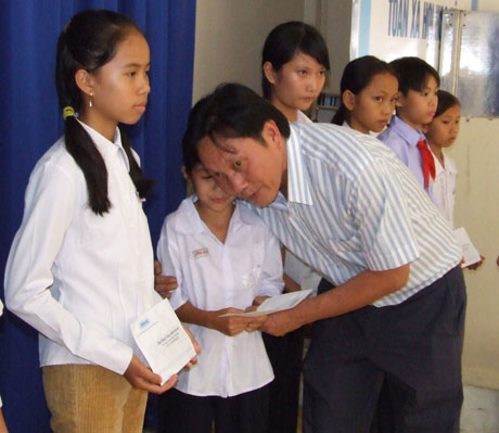 và ông Dương Ngọc Minh, Chủ tịch Hội đồng Quản trị Công ty cổ phần Hùng Vương trao học bổng cho các em. 