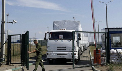 Một binh sỹ mở cửa biên giới để các xe tải chở hàng viện trợ vào Ukraine. Nguồn: AP