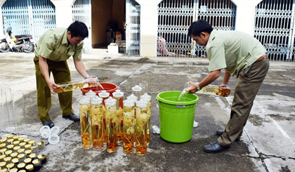 Lực lượng chức năng tiến hành tiêu hủy số rượu ngâm không rõ nguồn gốc xuất xứ. (Ảnh: Quang Thái/TTXVN)