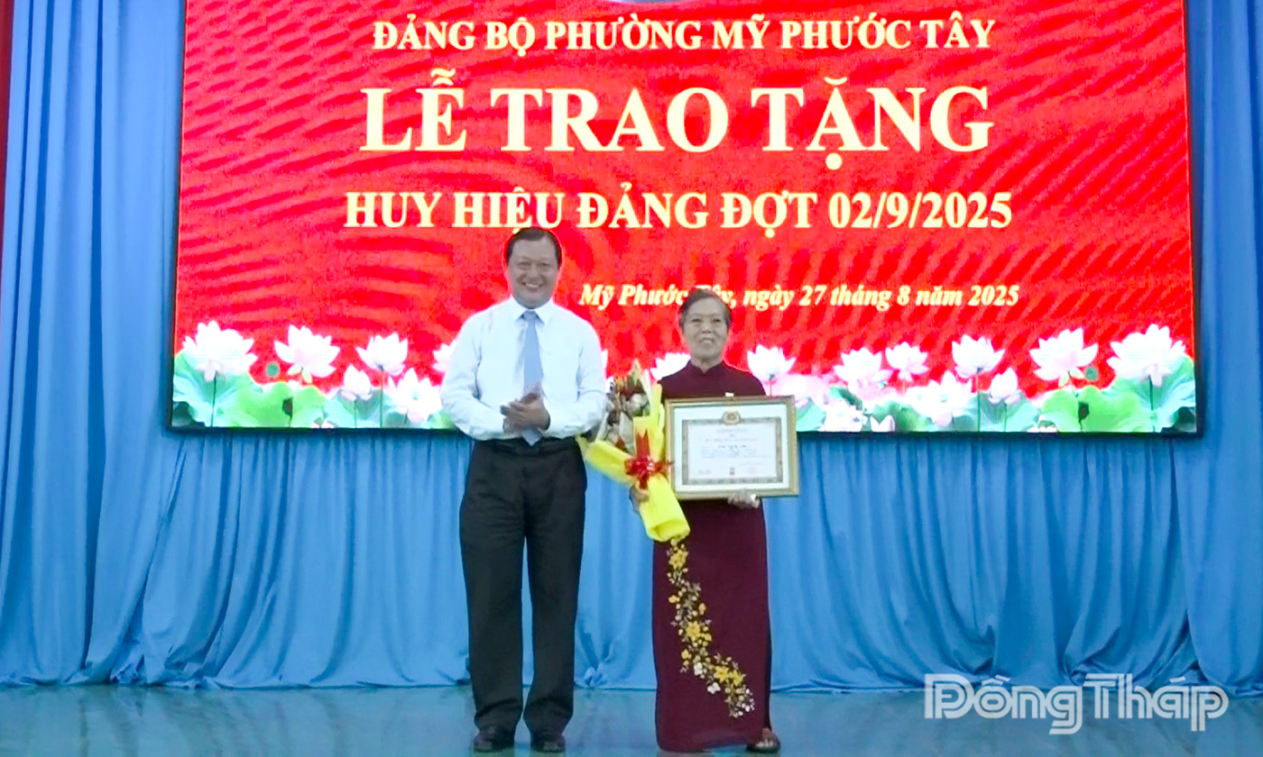 Đồng chí Phan Phùng Phú trao Huy hiệu 50 năm tuổi Đảng cho đảng viên Trần Thị Bé Tám.