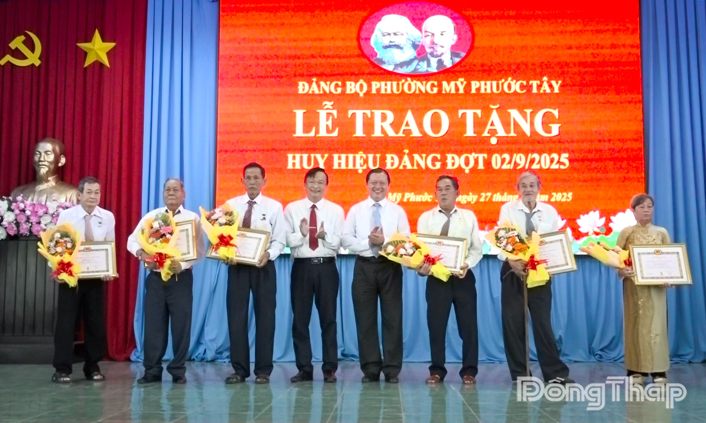 Đồng chí Phan Phùng Phú và đồng chí Lê Chí Thanh, Phó Bí thư Đảng ủy, Chủ tịch UBND phường Mỹ Phước Tây trao Huy hiệu 45 năm tuổi Đảng cho 6 đảng viên.