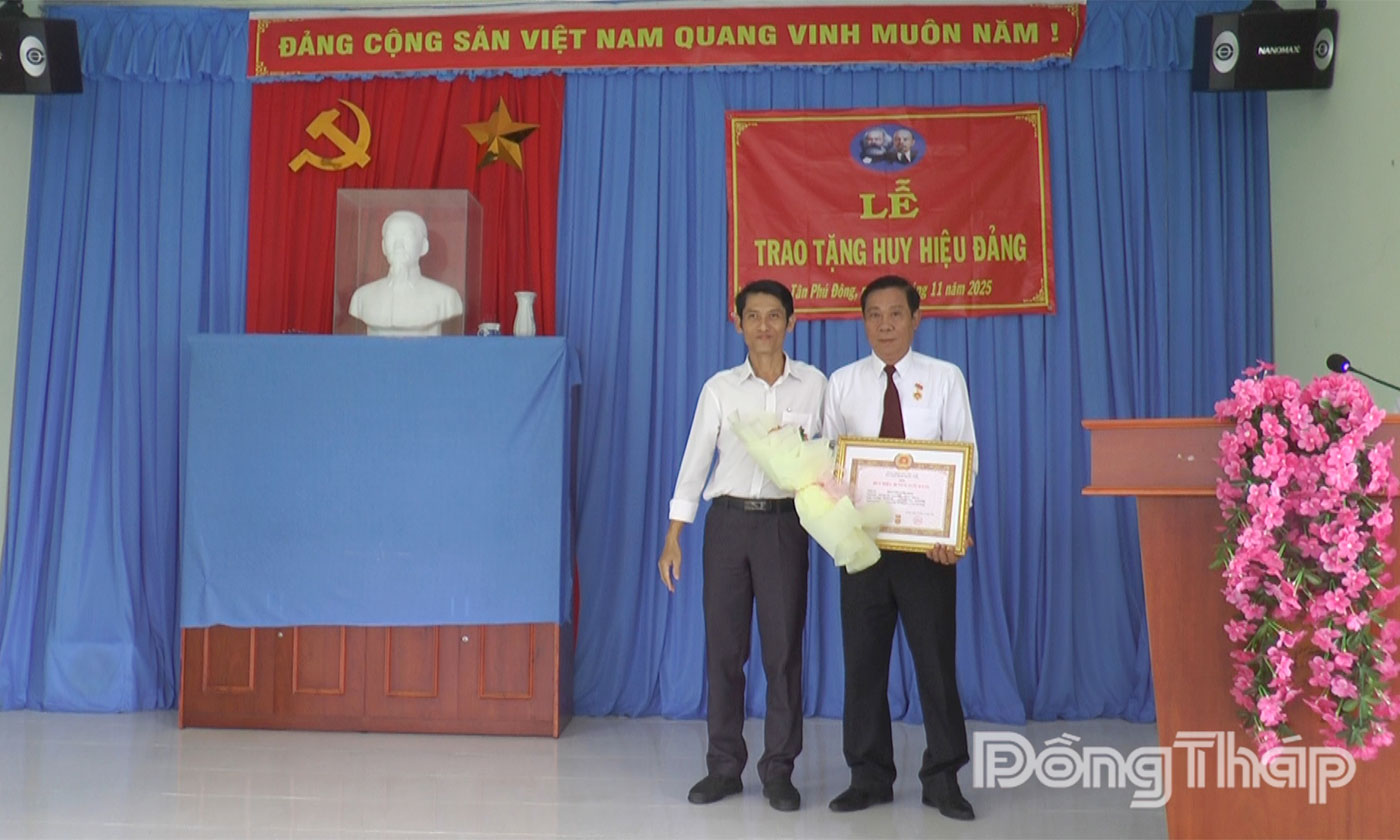 Đồng chí Huỳnh Thanh Bảo, Phó Bí thư Thường trực Đảng ủy xã Tân Phú Đông trao Huy hiệu 40 năm tuổi Đảng cho đồng chí Nguyễn Văn Hoa.