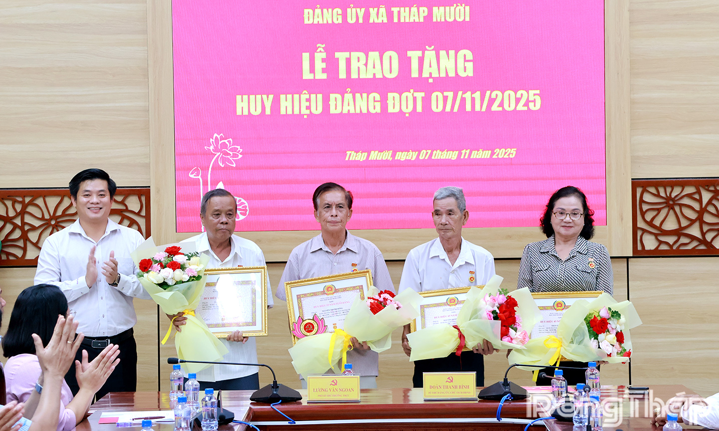 Ảnh: Bí thư Đảng ủy xã Tháp Mười Đoàn Thanh Bình (bìa trái) trao tặng Huy hiệu Đảng cho các đảng viên.